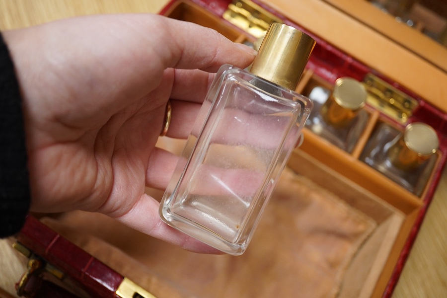 A red stained crocodile skin two layer vanity case, fitted with brass topped bottles and pots, case 22cm wide x 13.5cm high. Condition - handle has pulled away one side and needs re stitching